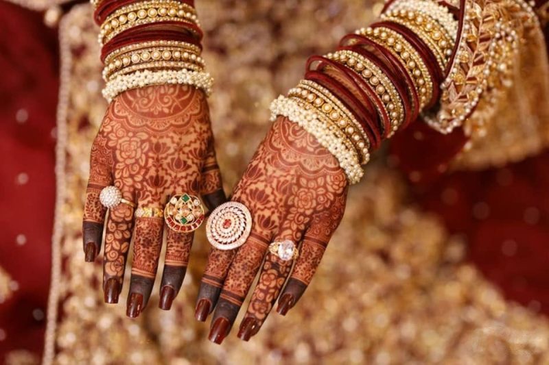 Detailed back-hand bridal mehndi design with floral jaali pattern and deep maroon stained fingertips