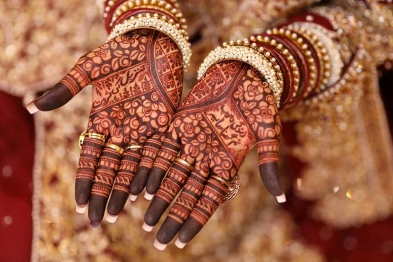 Traditional front palm bridal mehndi design with heavy floral patterns and dark natural stain